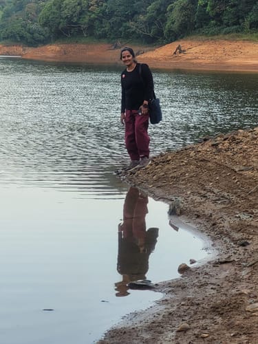 Reviewer wearing the Boxate Yoga Pants while standing on a muddy bank at the edge of a lake.