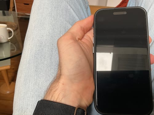 Rezensent hält ein iPhone, um die randgenaue Passform der 3-in-1-Schutzfolie zu zeigen.
