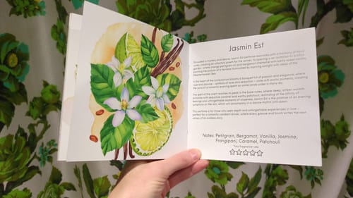 Reviewer holds the booklet from the Romantic Discovery Set open to the page for the 'Jasmin Est' scent.