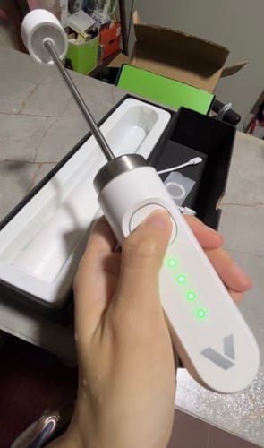 Customer holding a white Nanofoamer with its green indicator lights illuminated, over the product box.