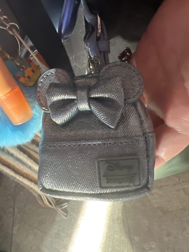 Reviewer holding the silver, glittery Minnie Mouse mini backpack keychain charm.