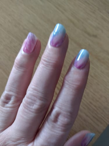 Nahaufnahme der Hand einer Kundin, die die aufgetragenen UV-Gel-Nagelfolien „Pastel Waves“ mit einem pastellfarbenen Verlauf zeigt.