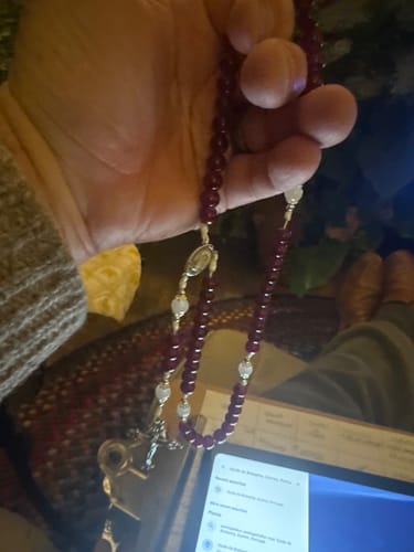 Customer holding the handmade Garnet Chalcedony Rosary, showing the polished dark beads and silver crucifix.