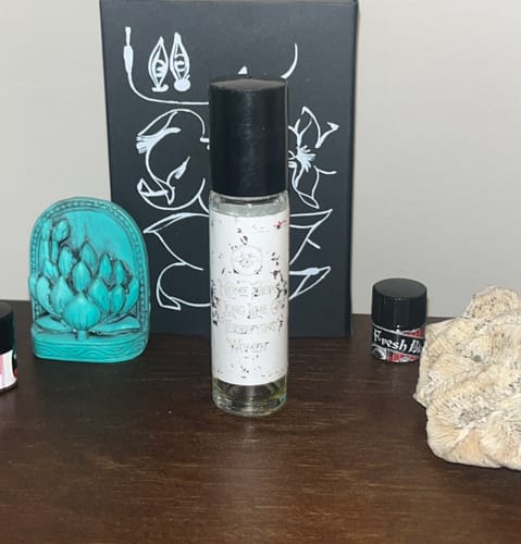 Reviewer's well-worn bottle of 'I Come From a Long Line of Terrifying Women' perfume oil on a wooden shelf.