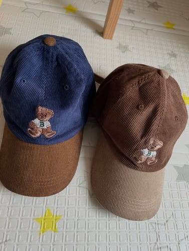 Customer's two corduroy Sweet Teddy Caps, one blue and one brown, shown side-by-side on a textured mat.