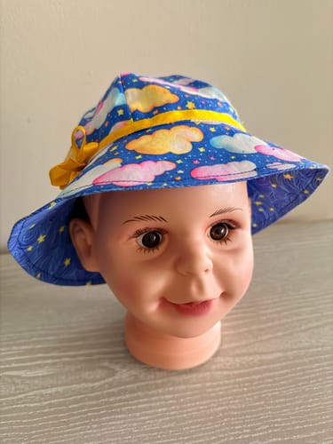 Reviewer's child's sun hat on a mannequin, showing the blue Stars and Clouds Fabric used as the inner lining on the brim.