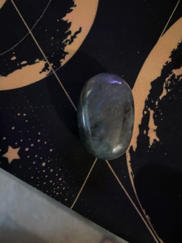 Customer's polished, dark meditation crystal resting on a black mat with gold celestial designs.