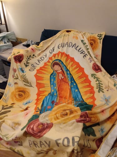 Customer's colorful Blessed Virgin of Guadalupe flannel blanket draped across a sofa, showing the full print.