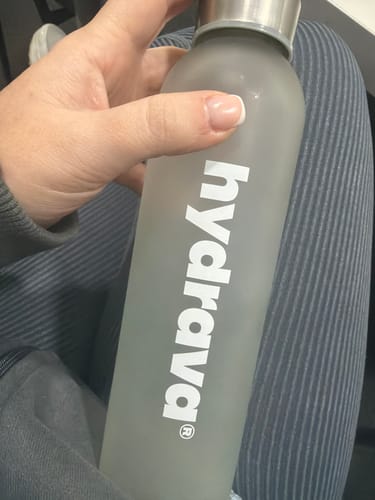 Customer holding the frosted glass Hydrava Bottle with a silver cap.