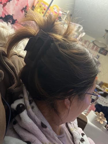 Reviewer showing their brown hair held up in a messy bun by a dark, flat hair clip.