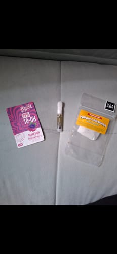 Customer's 10-OH HHC Superior Live Resin Cartridge in the Grape Soda strain, shown on a surface next to its packaging.