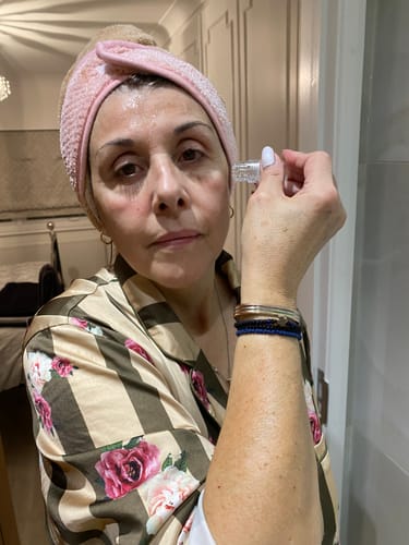 Reviewer in a pink headband applying The Micro Infusion System to their cheek.