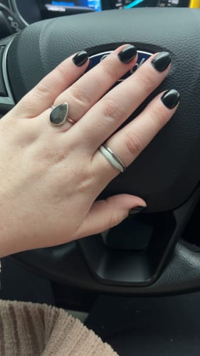 Reviewer's hand on a steering wheel, wearing the Layered Sahara Silver Ring on their ring finger.