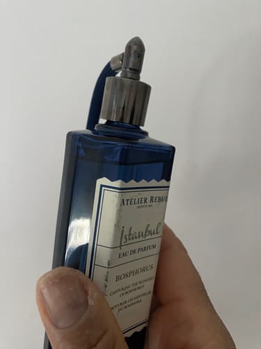 Recensent houdt de blauwe flacon Istanbul Bosphorus Eau De Parfum met de verstuiver vast.