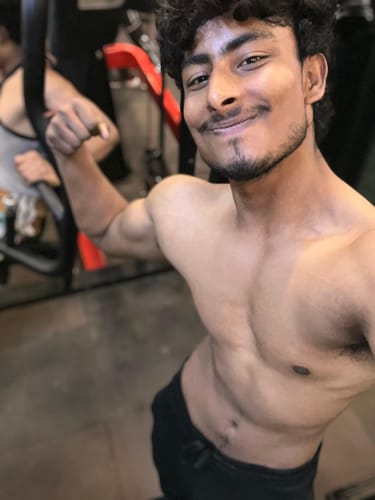 Reviewer in a gym flexing their bicep, showing results they attribute to Wellcore Micronised Creatine Monohydrate.