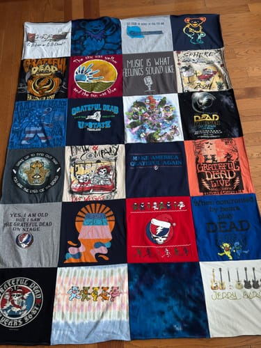 Customer's colorful Premium T-Shirt Quilt made from Grateful Dead themed shirts, laid flat on a wooden floor.