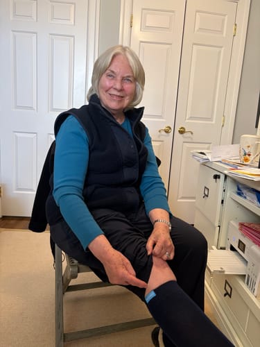 Reviewer sitting and pointing to the fit of their dark blue Performance Eucalyptus Compression Sock.