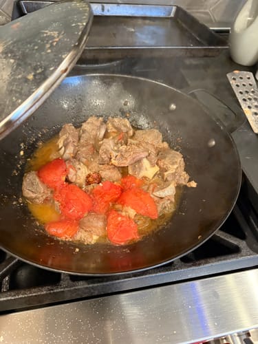 Customer's unrelated image showing meat and tomatoes cooking in a wok on a stovetop.