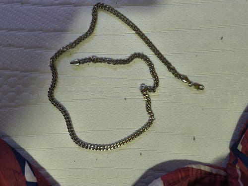 Un cliente muestra su Cadena Miami Cuban de 5mm sobre una superficie blanca con textura.