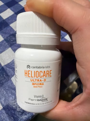 レビュアーが手に持っている「ヘリオケア ウルトラD」の白いボトル。