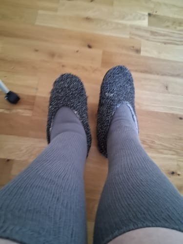 Kundens fötter och ben i grå Diasocks Komfortstrumpor, sedda uppifrån.