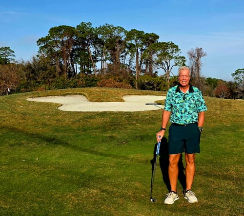 Reviewer wearing the Predator Jungle Camo polo while posing on a sunny golf course.