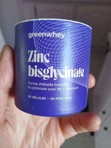 Client tenant dans sa main le pot bleu de Zinc Bisglycinate.