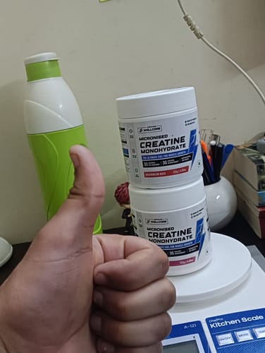 Customer gives a thumbs-up in front of two stacked tubs of Wellcore Micronised Creatine Monohydrate.