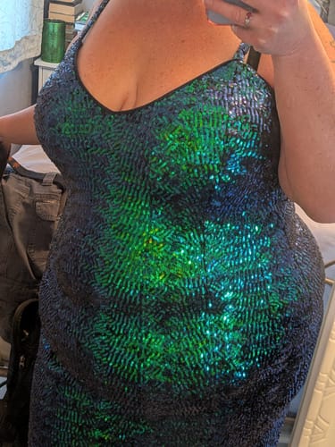 Close-up of a reviewer wearing the sparkly green Glitz & Glamour Dress, showing the fabric and fit on their torso.
