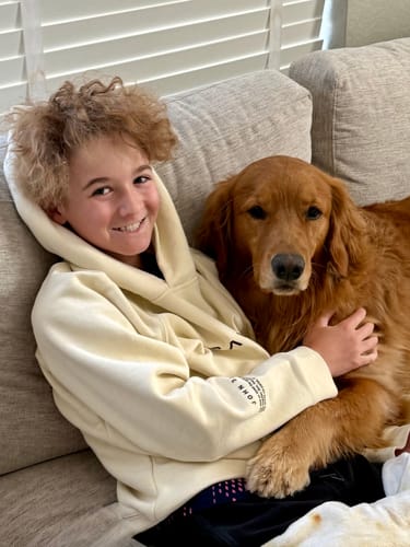 A reviewer smiling while wearing the cream Youth Oversized Hoodie, showing its relaxed fit and 'John 3:16' sleeve detail.