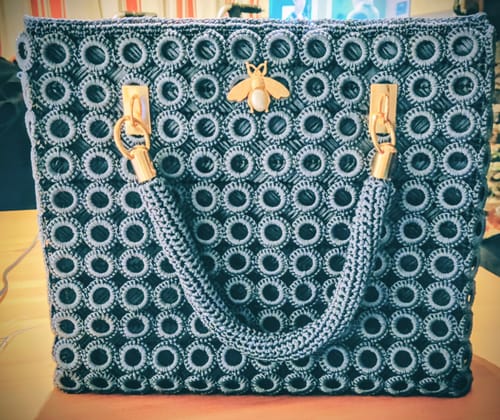 Customer's completed Garden Bee Crochet Bag in dark blue, featuring a crocheted circle pattern and gold bee detail.