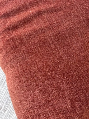 Klant toont een close-up van de geweven, terra-kleurige stof van de Ruby hoekbank.