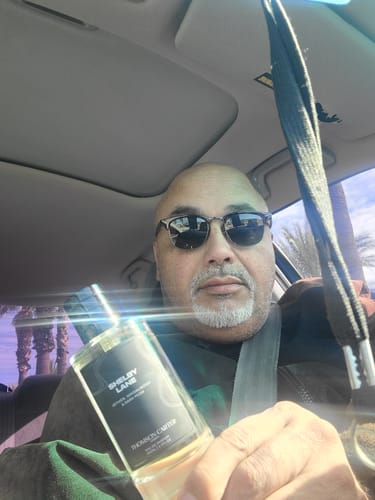 Reviewer holding a bottle of Shelby Lane Eau de Parfum while sitting in a car.
