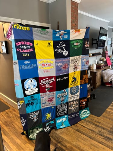 Customer's large Premium T Shirt Quilt displayed in a room, made from a colorful collection of running event t-shirts.