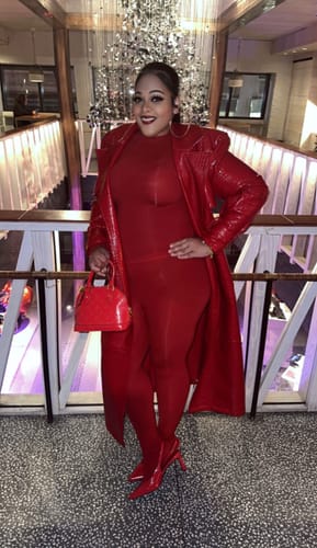 Customer posing in a shiny red Vegan Leather Croc Trench Coat indoors.