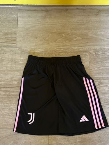 Recensore mostra il regalo segreto ricevuto: pantaloncini da calcio neri con strisce rosa.