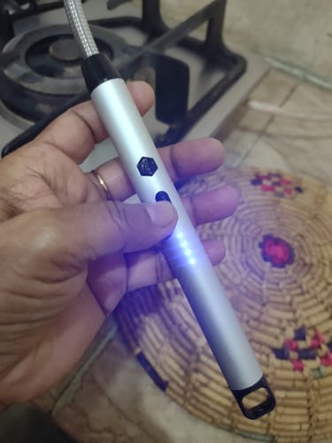 Customer holding the silver rechargeable electric lighter with its blue battery indicator lights illuminated.