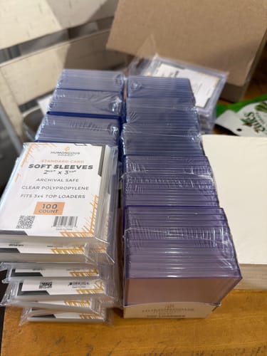 Customer's stacks of 180 Point Magnetic Holders, some shrink-wrapped and one in a retail box, on a wooden table.