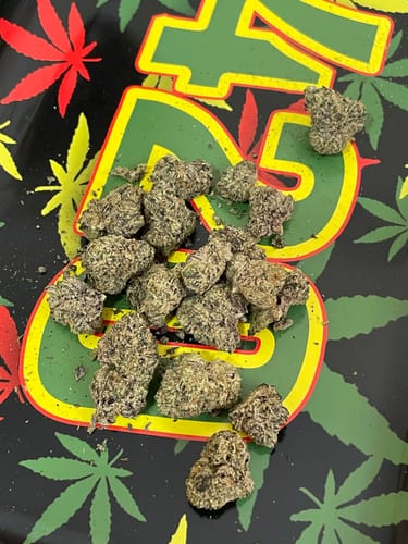 Customer's dense, purple Slurricane buds displayed on a colorful rolling tray.