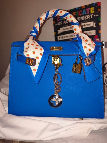 Customer's bright blue Kally Leather Bag personalized with a patterned scarf on the handle and a gold-tone charm.