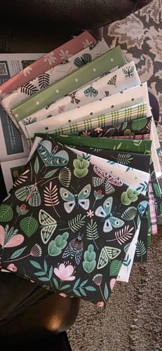 Customer's fanned-out fabric from the Mrs Quilty Subscription Box, showing vibrant floral and butterfly patterns.