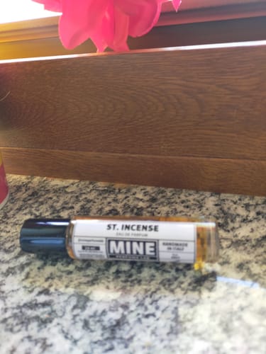 Il cliente mostra il profumo roll-on ST INCENSE appoggiato su un bancone di granito.