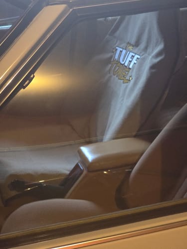 Customer's tan Waterproof Car Towel Seat Cover on a matching car seat, viewed through the car window.