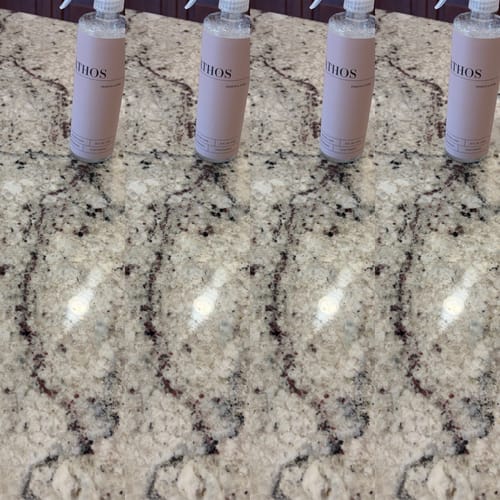 Customer's ÁTHOS spray bottles from the Business Introduction Bundle lined up on a shiny, clean stone countertop.