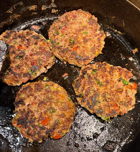 Customer's chapli kababs, made with the grass-fed ground beef, cooking in a black skillet.