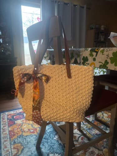 Customer's completed Aveline crochet Shoulder Bag in a light color with leather straps, hanging on a chair.