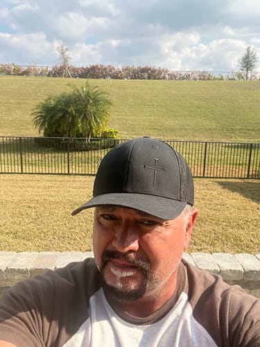 A reviewer wearing the black Nail Cross hat outdoors. The sturdy hat holds its shape well, showing the front panel and mesh back.