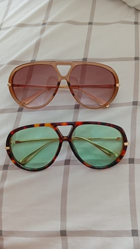 Foto do cliente mostrando os óculos Tropea com armação tartaruga e lentes verdes ao lado de outro par.