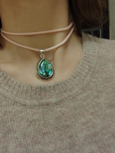 Reviewer wearing the teardrop crystal pendant with its blue-green stone on a new pink cord.