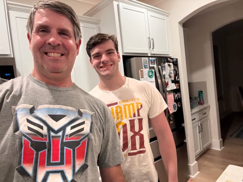 Reviewer smiling while wearing the grey Retro Autobot Logo Transformers T-Shirt.